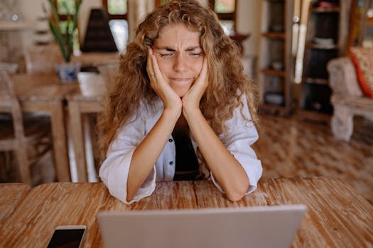 Person using a laptop with a thoughtful expression